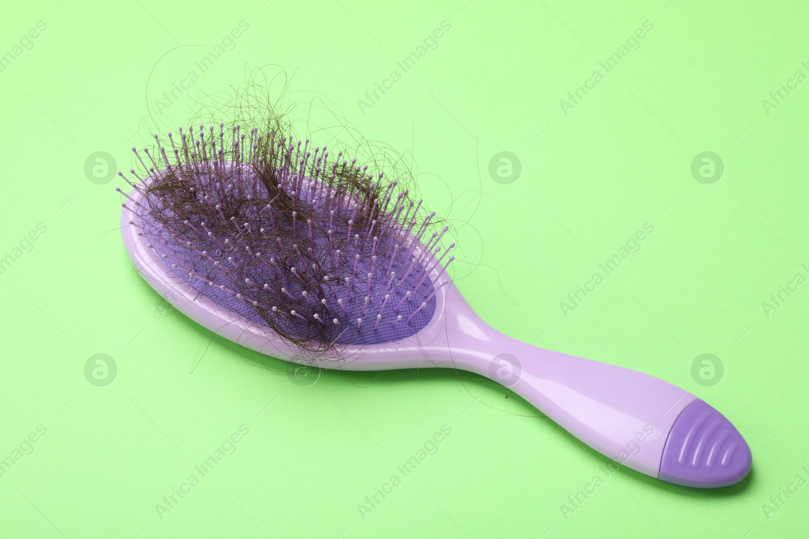 Photo of One brush with lost hair on light green background. Alopecia problem