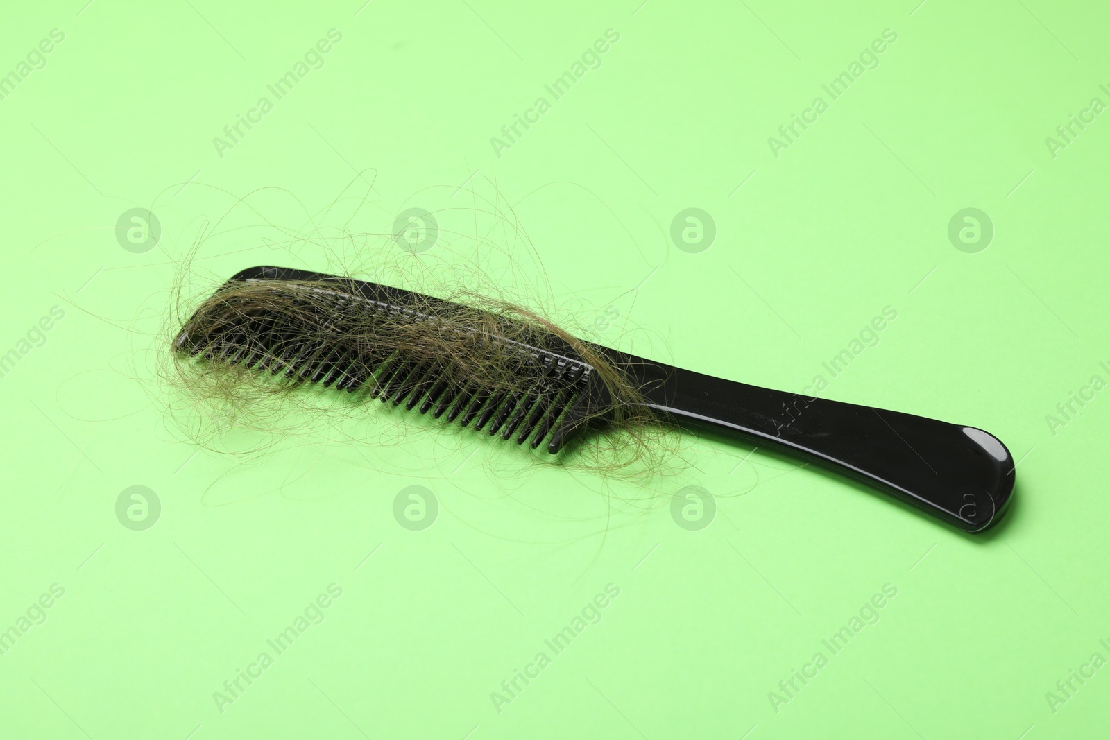 Photo of One comb with lost hair on light green background. Alopecia problem