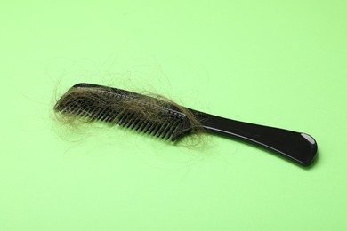 One comb with lost hair on light green background. Alopecia problem