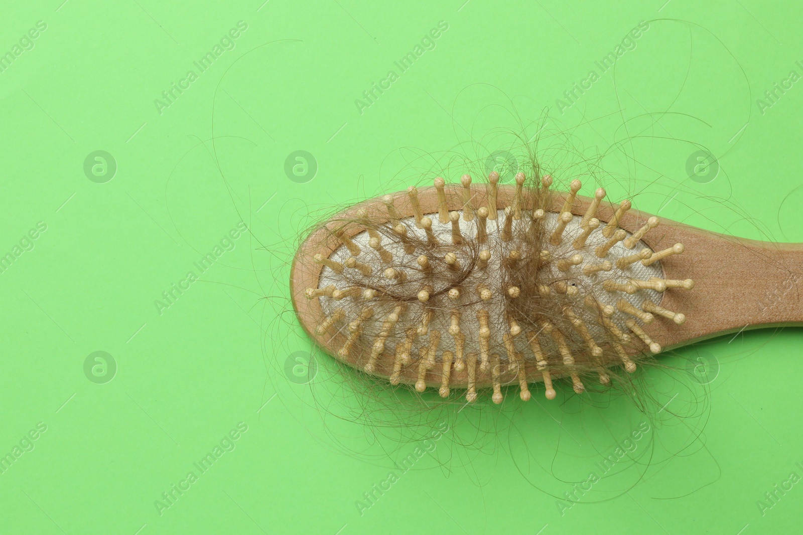 Photo of One brush with lost hair on light green background, top view. Space for text