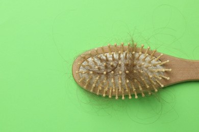 Photo of One brush with lost hair on light green background, top view. Space for text