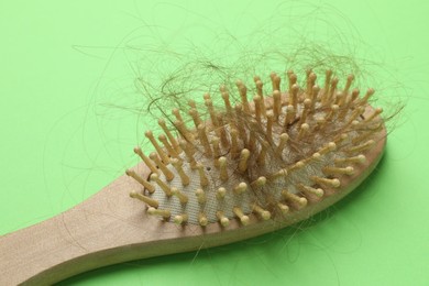 Photo of One brush with lost hair on light green background. Alopecia problem