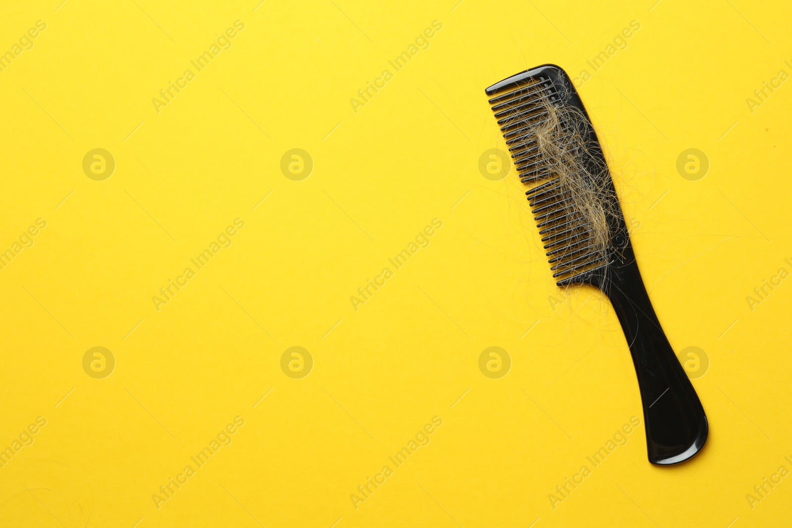 Photo of One comb with lost hair on yellow background, top view. Space for text