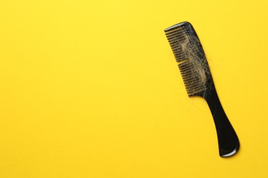 Photo of One comb with lost hair on yellow background, top view. Space for text