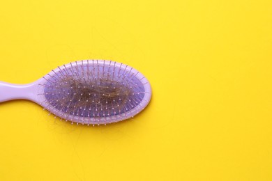 One brush with lost hair on yellow background, top view. Space for text