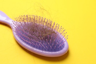 Photo of One brush with lost hair on yellow background. Alopecia problem