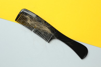 Photo of One comb with lost hair on color background, top view. Alopecia problem