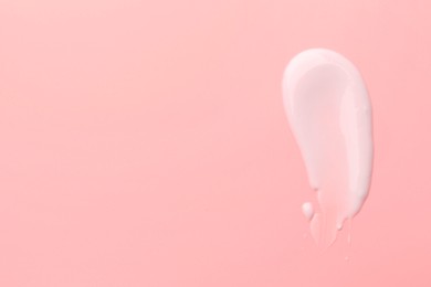 Photo of Sample of face cream on pink background, top view. Space for text