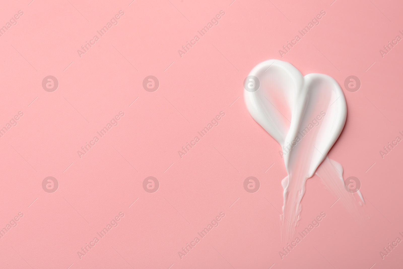 Photo of Sample of face cream on pink background, top view. Space for text