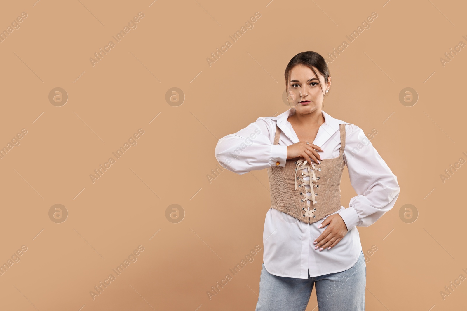 Photo of Beautiful woman in stylish corset posing on beige background. Space for text