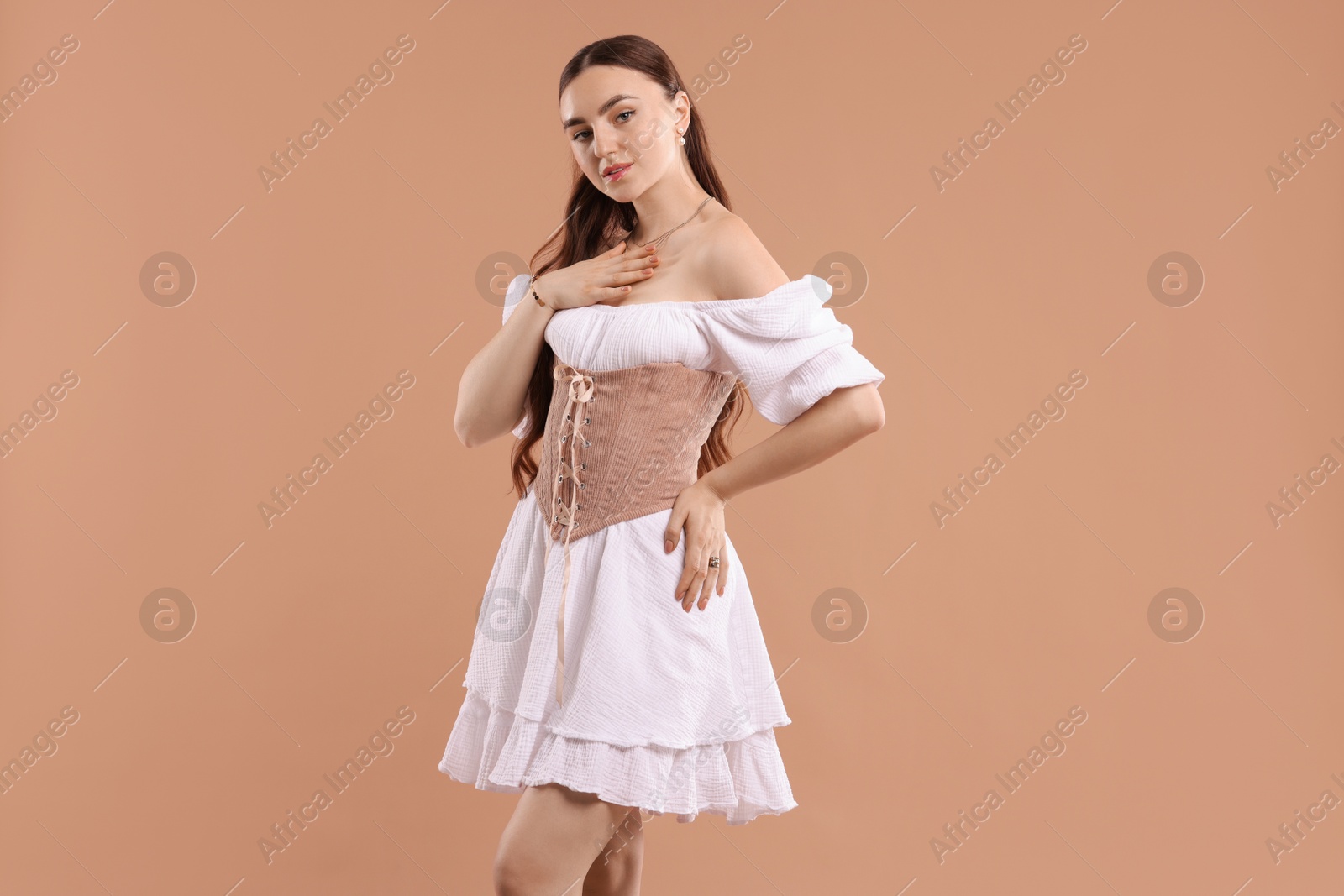 Photo of Beautiful woman in velvet corset posing on beige background