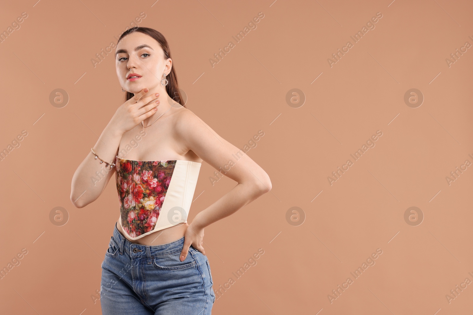 Photo of Beautiful woman in stylish corset posing on beige background. Space for text