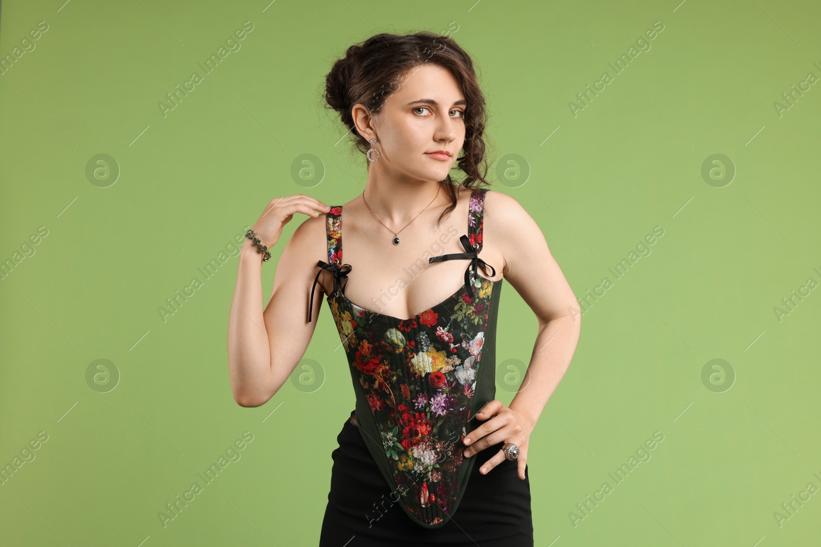 Photo of Beautiful woman in stylish corset posing on green background