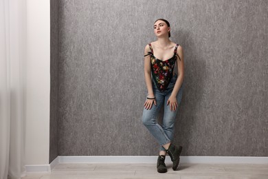 Photo of Beautiful young woman in stylish corset near grey wall