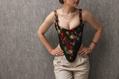 Photo of Woman in stylish corset near grey wall, closeup