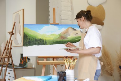 Photo of Woman drawing landscape with brush in studio