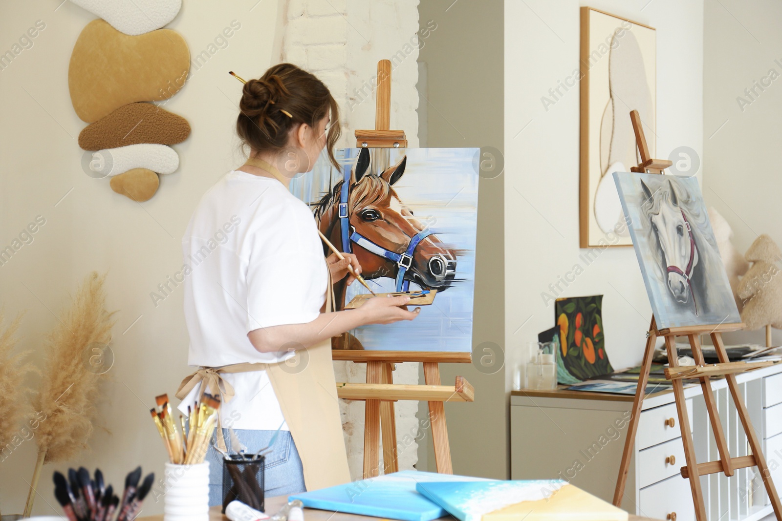 Photo of Woman drawing cute horse with brush in studio