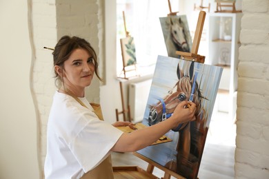 Woman drawing cute horse with brush in studio