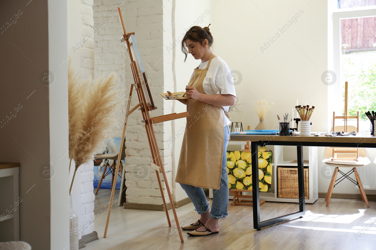 Photo of Woman drawing on easel with canvas in studio