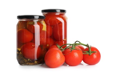 Photo of Tasty pickled tomatoes in jars and vegetable isolated on white