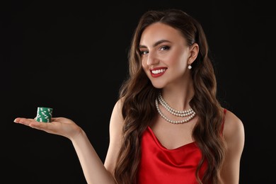 Photo of Smiling woman with poker chips on black background