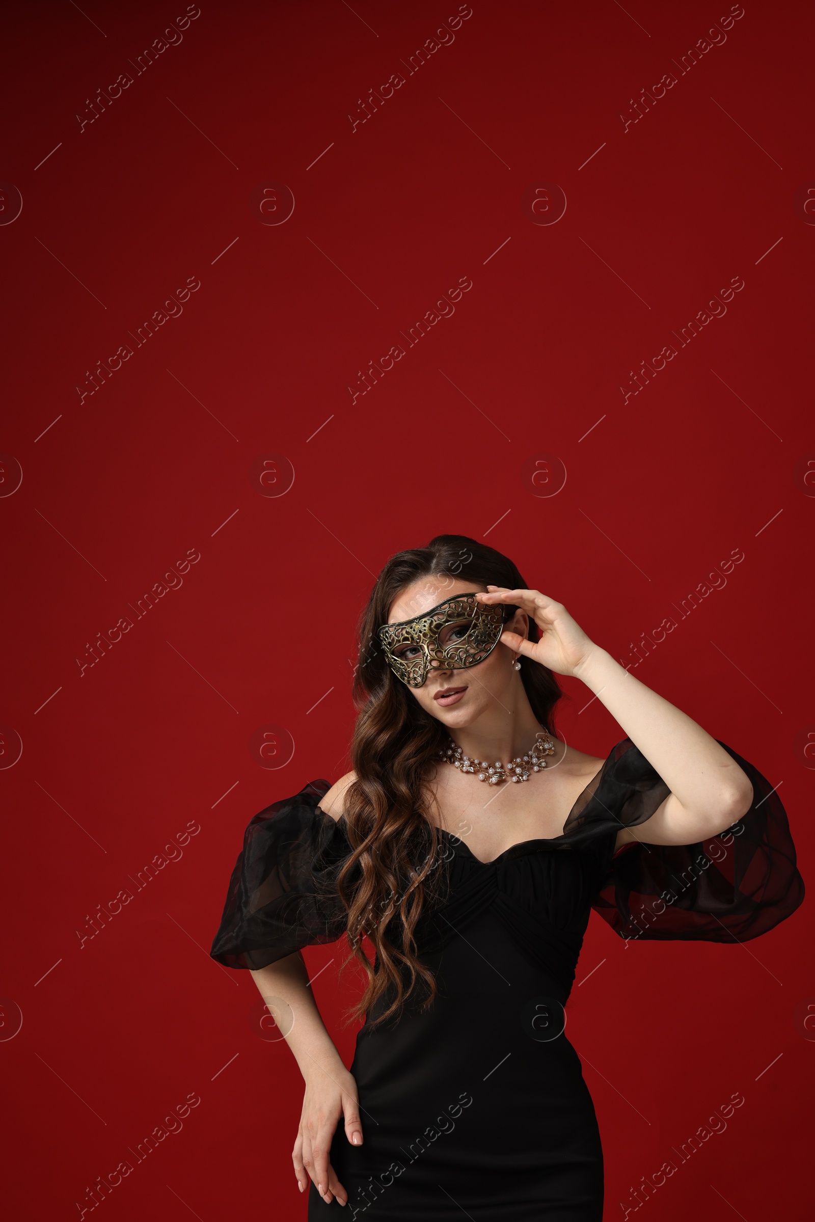 Photo of Beautiful woman wearing carnival mask on red background. Space for text