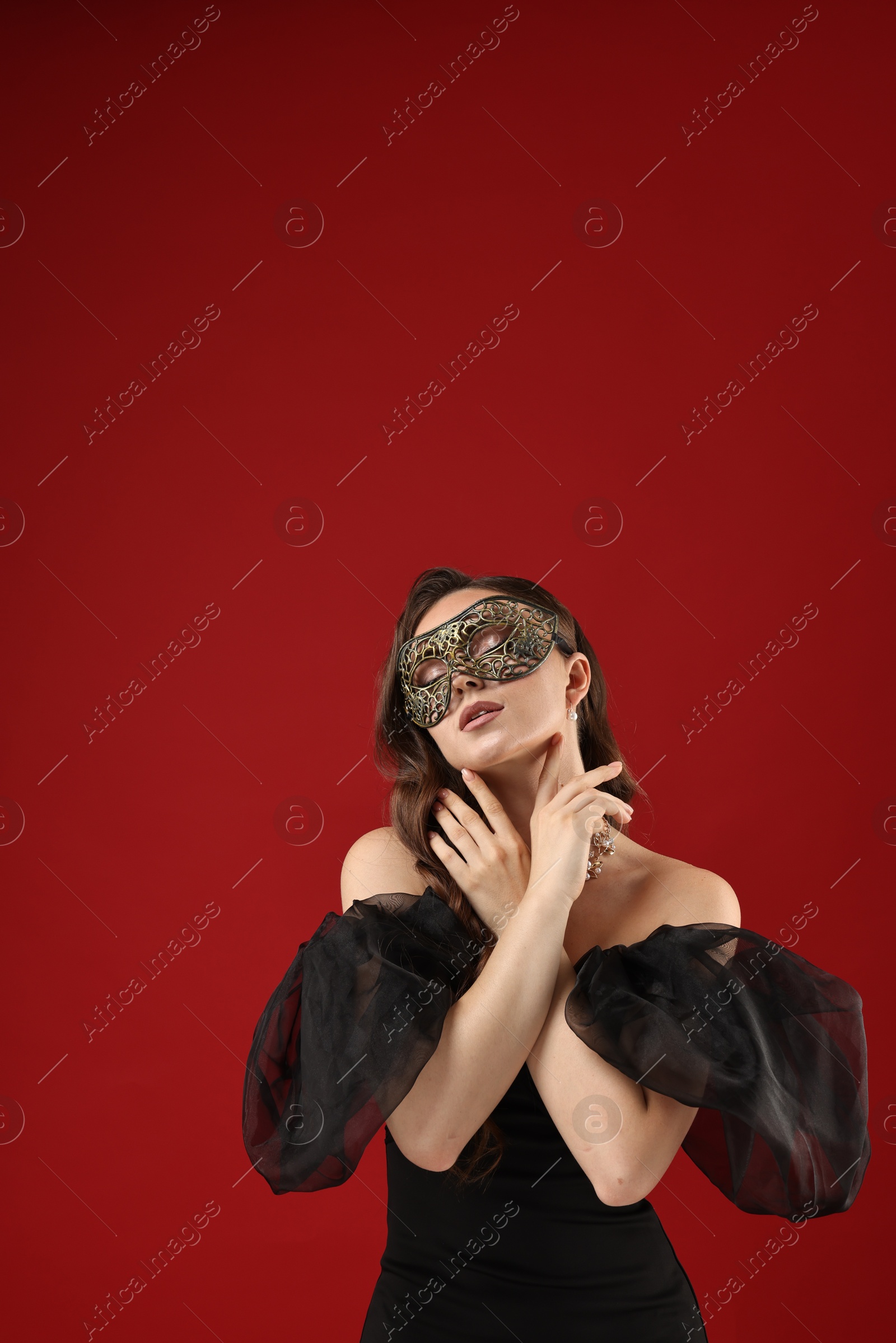 Photo of Beautiful woman wearing carnival mask on red background. Space for text