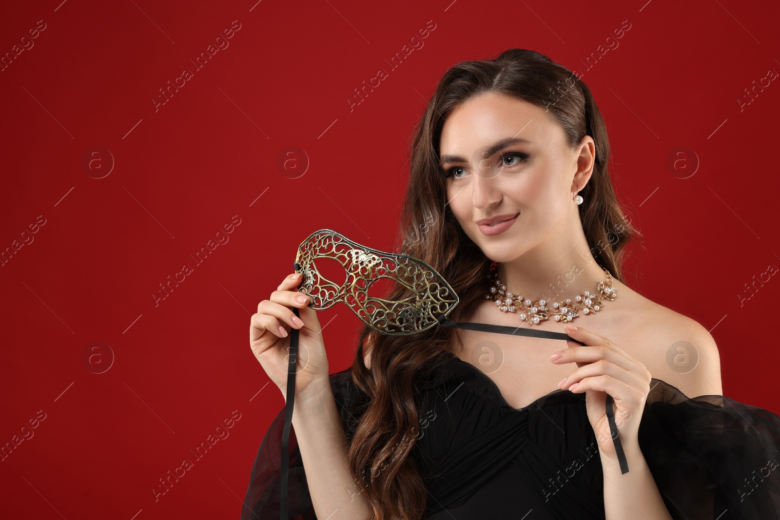 Photo of Beautiful woman with carnival mask on red background. Space for text