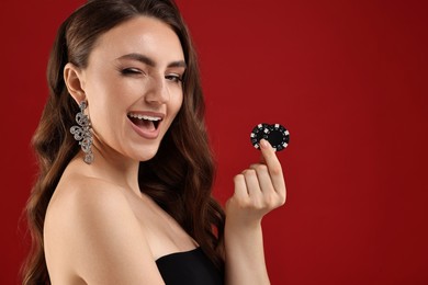 Photo of Happy woman with poker chips on red background. Space for text