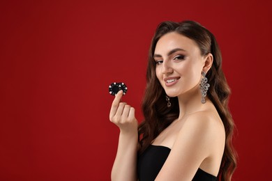 Photo of Smiling woman with poker chips on red background. Space for text