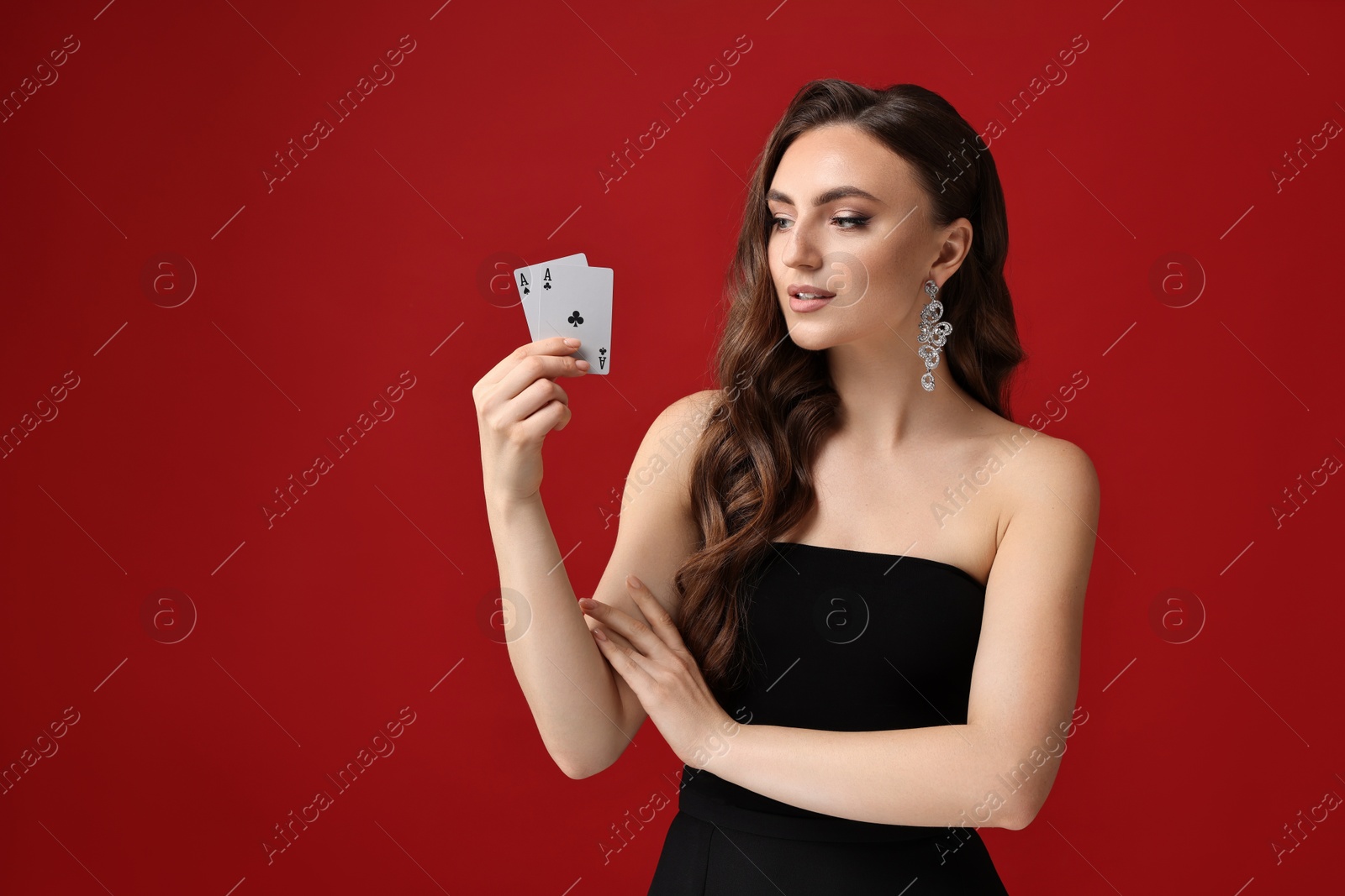 Photo of Poker game. Charming woman with playing cards on red background. Space for text