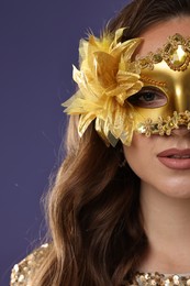 Photo of Beautiful woman wearing carnival mask on purple background, closeup