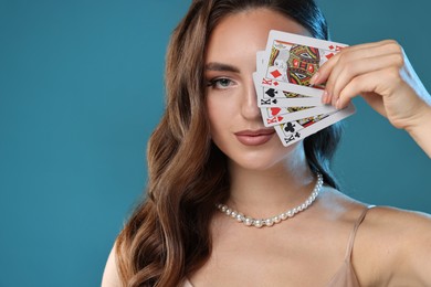 Photo of Poker game. Charming woman covering eye with playing cards on light blue background. Space for text