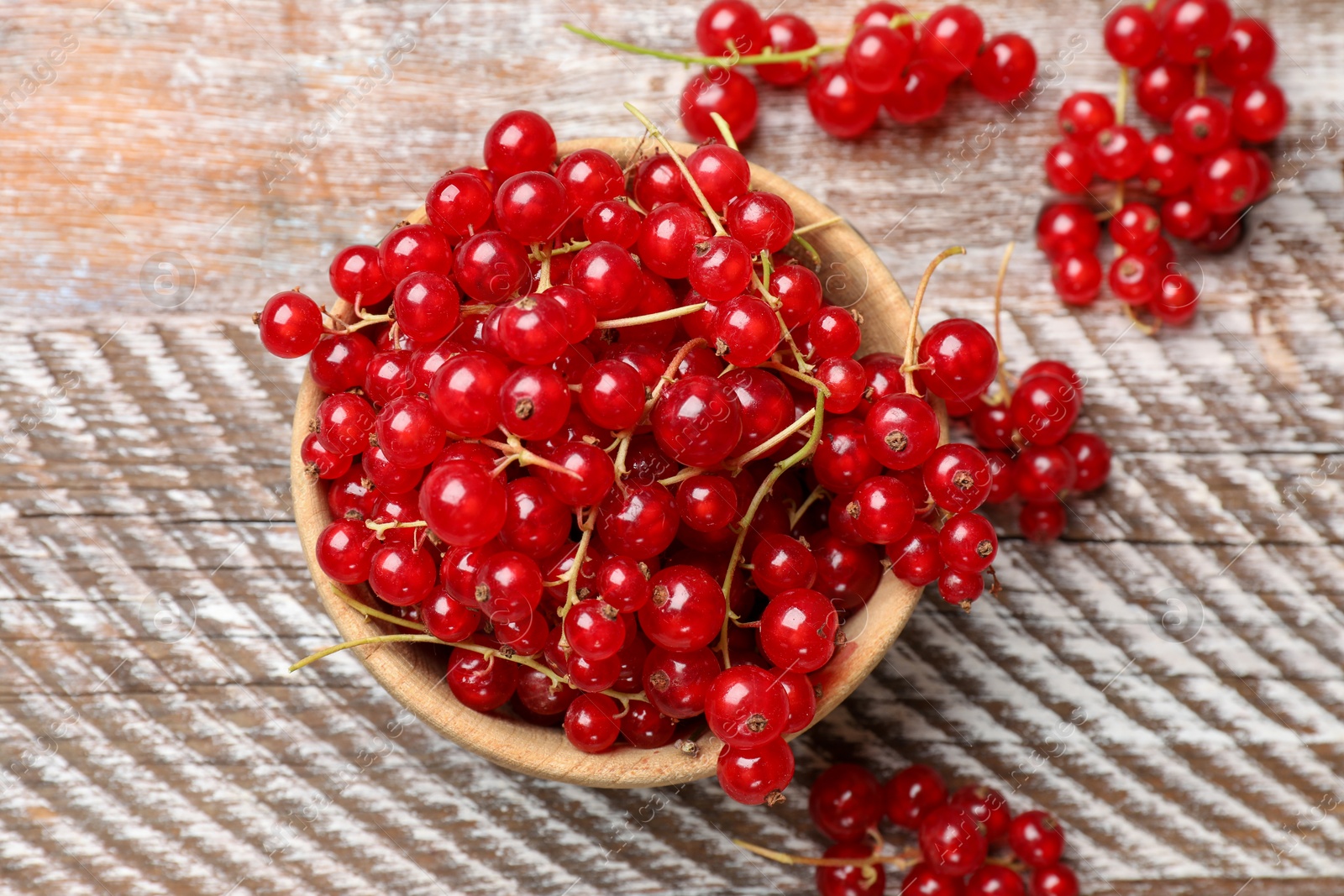 Photo of Fresh red currant berries in bowl on wooden table, top view