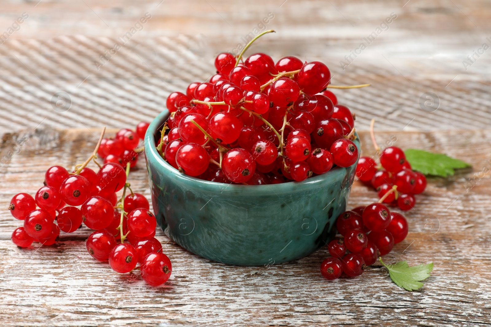 Photo of Fresh red currant berries in bowl on wooden table, closeup