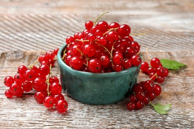 Fresh red currant berries in bowl on wooden table, closeup