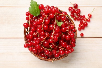 Photo of Fresh red currant berries in basket on white wooden table, top view