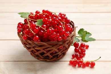 Photo of Fresh red currant berries in basket on white wooden table, closeup