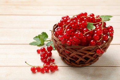 Photo of Fresh red currant berries in basket on white wooden table, closeup