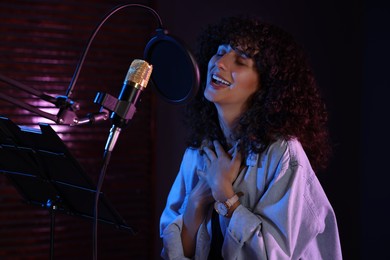 Photo of Vocalist singing into microphone in professional record studio