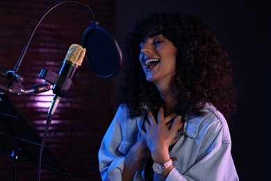 Photo of Vocalist singing into microphone in professional record studio