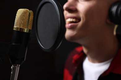 Photo of Vocalist singing into microphone in professional record studio, closeup
