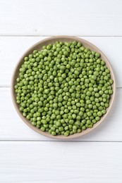 Photo of Fresh green peas in plate on white wooden table, top view