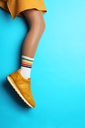 Woman wearing sneakers on light blue background, closeup