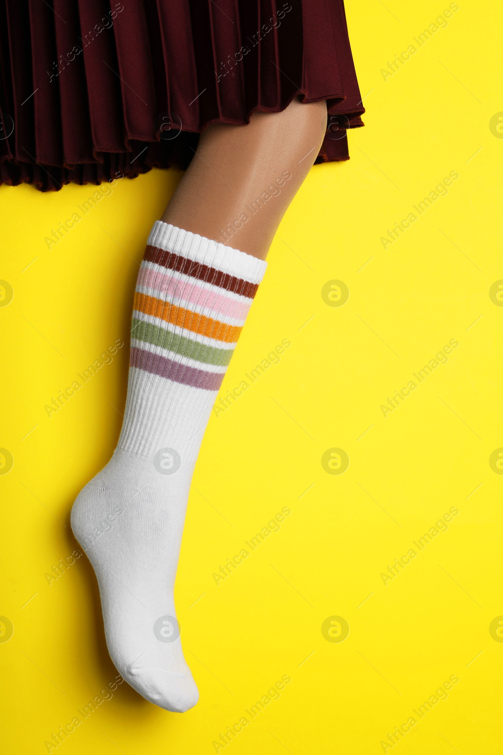 Photo of Woman wearing color sock on yellow background, closeup