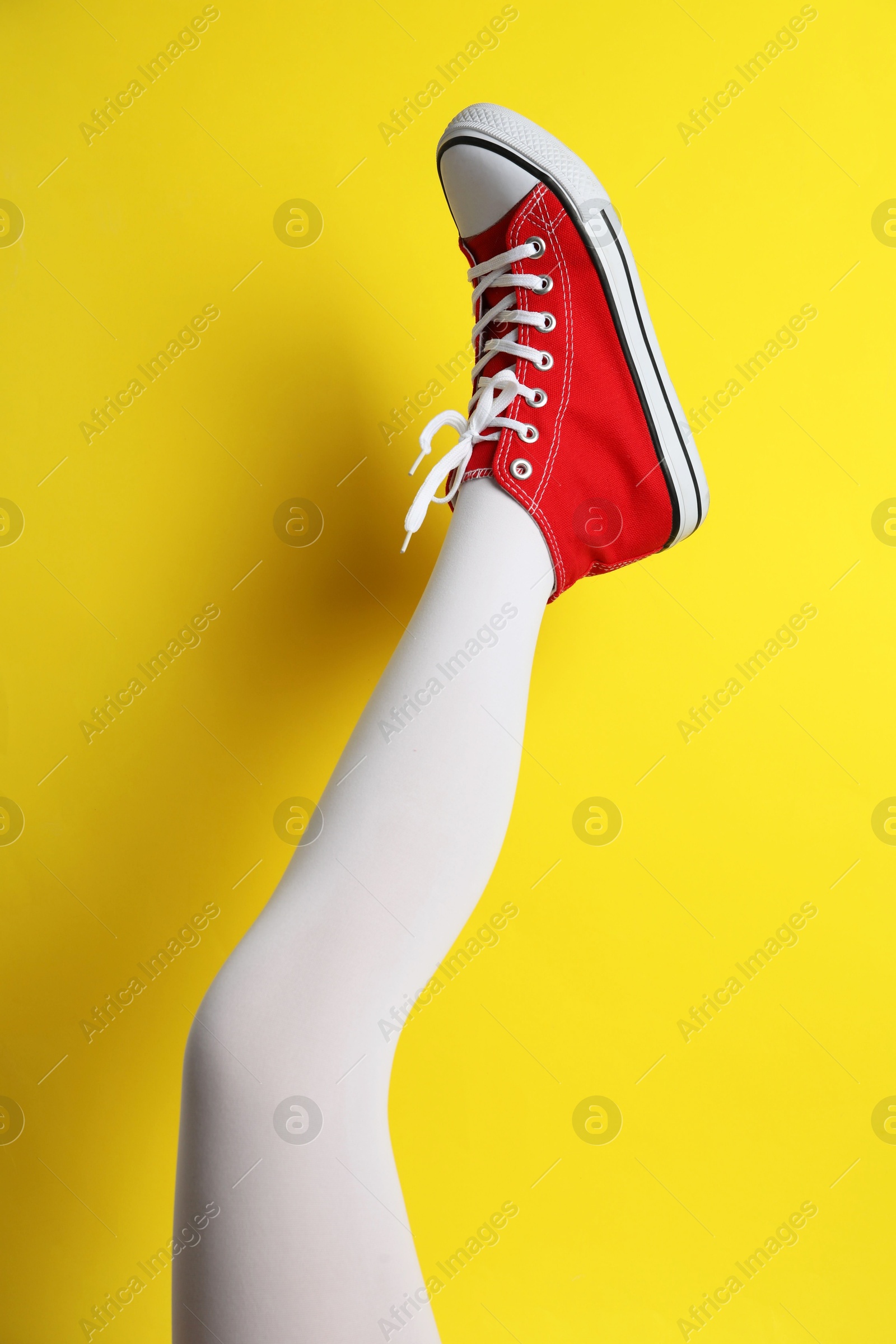 Photo of Woman wearing shoes on yellow background, closeup