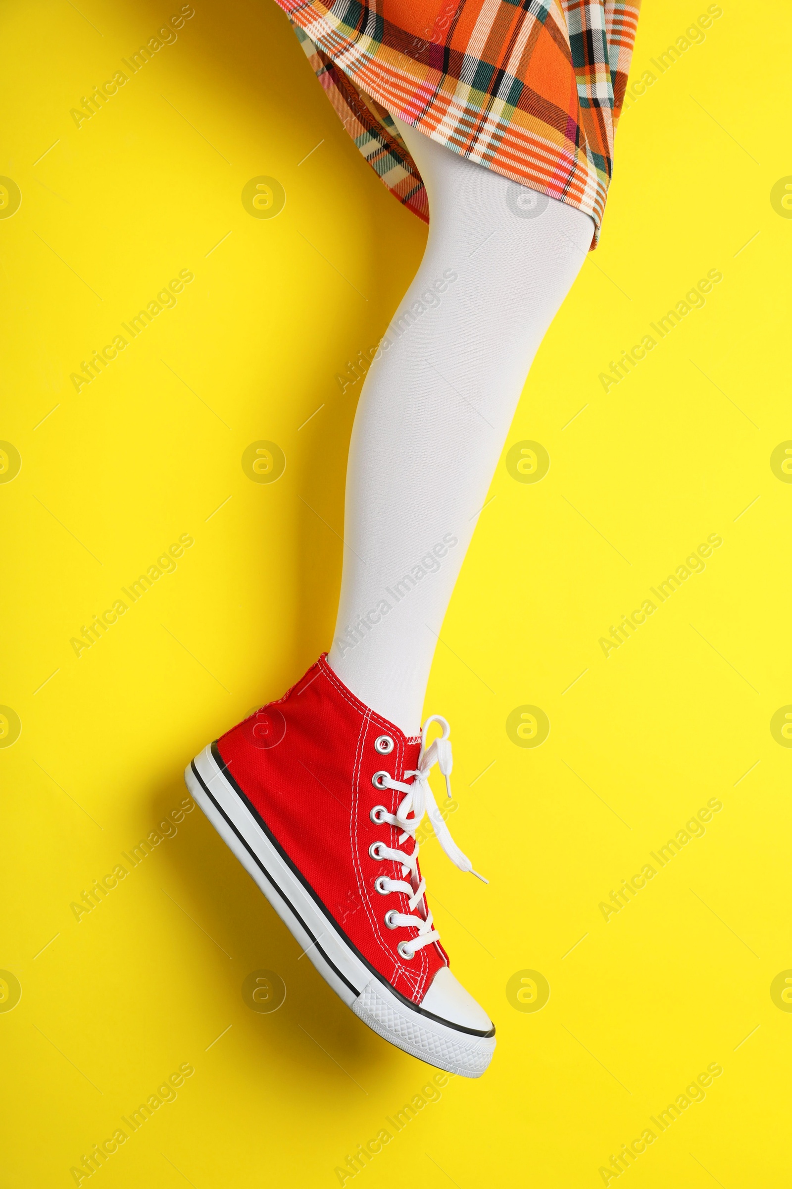 Photo of Woman wearing shoes on yellow background, closeup