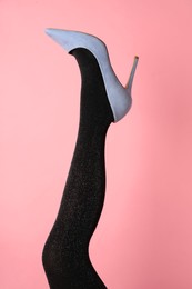 Woman wearing black tights and high heel shoe on pink background, closeup