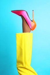 Woman wearing high heel shoe on light blue background, closeup