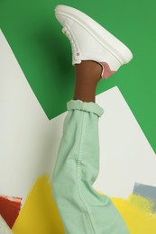 Photo of Woman wearing sneakers on color background, closeup